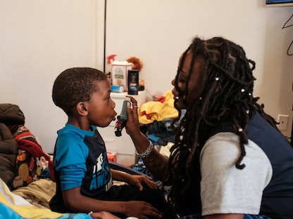 سيدة تعطي ابنها علاجاً من الربو قبل ذهابه إلى المدرسة في واشنطن- 25 يناير 2019 - REUTERS