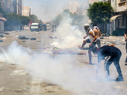 محتجون وسط أدخنة غاز مسيل للدموع أطلقتها الشرطة لتفريقهم في منطقة تطاوين التونسية، 21 يونيو 2020 - AFP