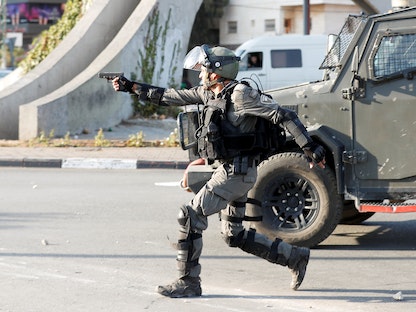 جندي إسرائيلي يصوب مسدسه إلى متظاهرين بالقرب من مستوطنة بيت إيل في الضفة الغربية المحتلة، 11 نوفمبر 2021 - REUTERS
