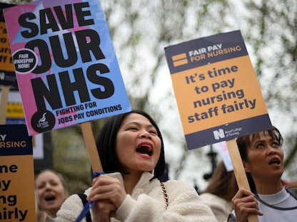عاملون في الرعاية الصحية يحملون لافتات خلال تظاهرة على جسر وستمنستر في لندن. 1 مايو 2023  - AFP