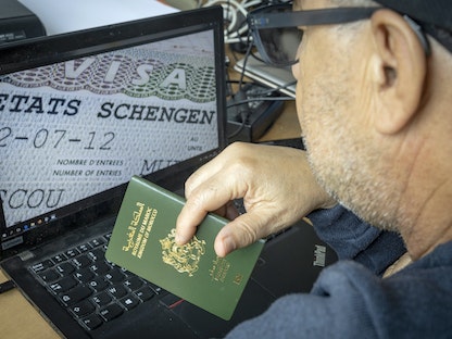 مغربي يحمل جواز سفره أمام جهاز كمبيوتريعرض تأشيرة شنجن. 28 سبتمبر 2021 - AFP