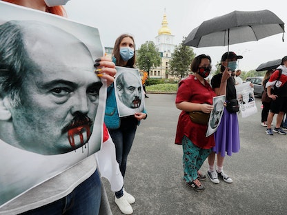 ناشط يرفع ملصقات تحمل وجه الرئيس البيلاروسي ألكسندر لوكاشينكو في مظاهرة لدعم الحركة البيلاروسية في كييف بأوكرانيا- 28 مايو 2021. - REUTERS