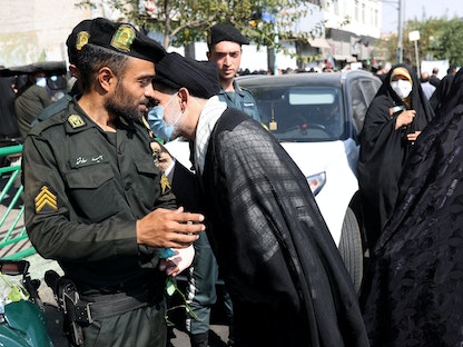 رجل دين موال للحكومة يعانق شرطياً خلال مسيرة ضد التجمعات الاحتجاجية الأخيرة في إيران، بعد صلاة الجمعة في طهران، إيران. 23 سبتمبر 2022. - REUTERS