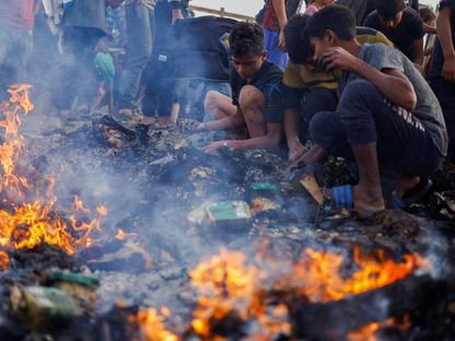 أطفال فلسطينيون يبحثون عن الغذاء بين رماد خيام أحرقتها غارة إسرائيلية على منطقة مخصصة للنازحين في رفح جنوبي قطاع غزة. 27 مايو 2024 - REUTERS