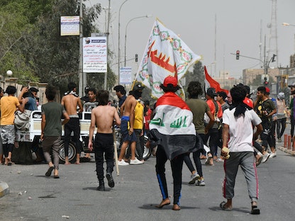 متظاهرون عراقيون يتجمعون لإغلاق أحد شوارع مدينة الناصرية، خلال تظاهرة مناهضة للحكومة - 10 مايو 2020 - AFP
