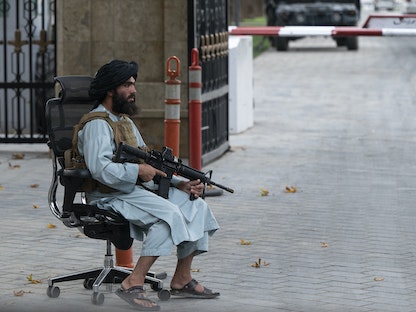 مقاتل من طالبان يحرس بوابة القصر الرئاسي السابق بعد اجتماع حضره رئيس الوزراء محمد حسن أخوند في كابول- 13 أغسطس 2022 - AFP