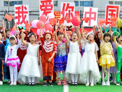 تلاميذ في مدرسة ابتدائية بمنغوليا الداخلية يحملون أعلاماً صينية ولافتات كُتب عليها "أحب الصين" احتفالاً بالعيد الوطني - 27 سبتمبر 2020 - REUTERS