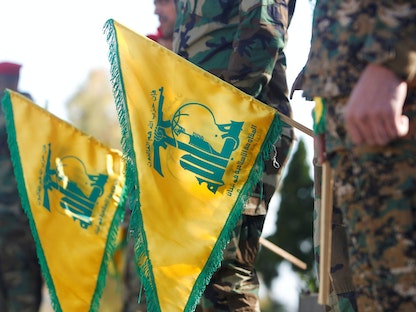 عناصر من "حزب الله" اللبناني يرفعون شعارات الحزب خلال مناسبة في كفركلا جنوب لبنان- 25 مايو 2021 - REUTERS