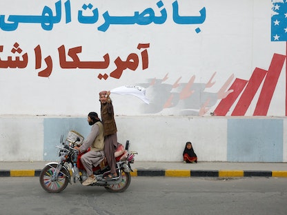 مؤيّدان لحركة "طالبان" بالذكرى الأولى لسقوط كابول فيما تجلس فتاة صغيرة تبكي على رصيف الطريق. 15 أغسطس 2022 - REUTERS