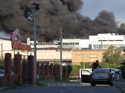 رجل يشاهد سحابة دخان بعد ضربة صاروخية على مستودع لشركة صناعية وتجارية في أوديسا– 16 يوليو 2022 - AFP
