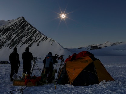 أشخاص يرصدون كسوفاً للشمس من المحطة القطبية العلمية Glaciar Union في أنتاركتيكا ، على الأراضي التشيلية - 4 ديسمبر 2021. - REUTERS