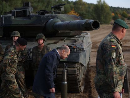 المستشار الألماني أولاف شولتز بجوار دبابة من طراز "ليوبارد 2" أثناء زيارة لقوات الجيش الألماني خلال مناورات تدريبية في أوستينهولتس شمال ألمانيا. 17 أكتوبر 2022 - AFP