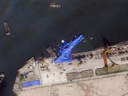 صورة قمر اصطناعي تظهر سفينة حربية كورية شمالية مغطاة بقماش أزرق بعد حادث وقع أثناء إطلاقها في حوض بناء السفن في تشونغجين، كوريا الشمالية. 23 مايو 2025. - Reuters