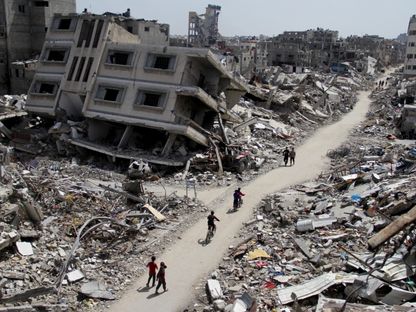 فلسطينيون يركبون دراجات عبر أنقاض المنازل والمباني التي دمرت خلال الحرب الإسرائيلية على غزة شمال قطاع غزة. 31 مارس، 2024. - Reuters