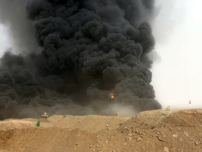 عمال يقفون بالقرب من حريق في بئر نفط على بعد 600 جنوب غرب طهران. 9 يونيو 2010 - REUTERS