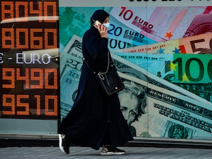تسير قرب شاشة تعرض أسعار العملات أمام مكتب صرافة في إسطنبول - 26 أكتوبر 2020 - AFP