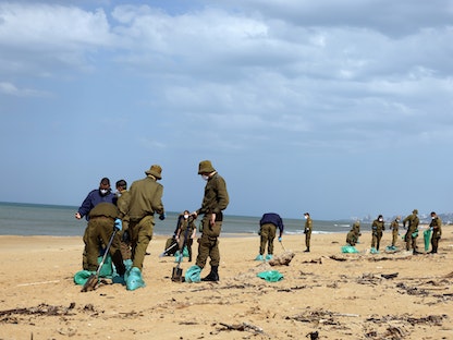 جنود إسرائيليون ينظفون القطران من الرمال في شاطئ عتليت شمالاً، بعد تسرب نفطي - 22 فبراير 2021 - REUTERS