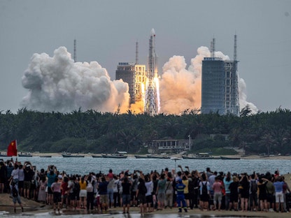 صينيون يشاهدون لحظة انطلاق صاروخ "لونغ مارش 5 بي" يحمل الوحدة الأساسية لمحطة تيانخه الفضائية الصينية في مقاطعة هاينان - 29 أبريل 2021 - AFP