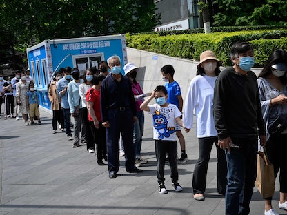 أشخاص يصطفون في طابور للخضوع لاختبار فيروس كورونا خارج مركز تسوق في العاصمة الصينية بكين. 5 مايو 2022 - AFP