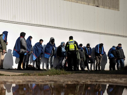 عناصر الشرطة البريطانية يرافقون مهاجرين بعد وصولهم إلى بريطانيا عبر القناة الإنجليزية. 15 مارس 2022. - AFP