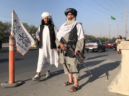 مقاتلان من حركة طالبان يقفان أمام مقر وزارة الداخلية في كابول بعد السيطرة على العاصمة - 16 أغسطس 2021 - REUTERS