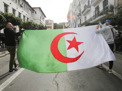 متظاهرون يرفعون العلم الوطني خلال مظاهرة في العاصمة الجزائر تطالب بالتغيير السياسي- 2 أبريل 2021 - REUTERS
