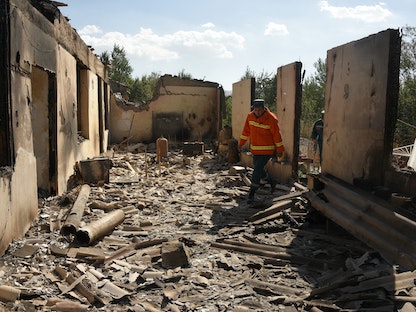 رجل إطفاء يعمل وسط أنقاض منزل أصيب بقصف أذربيجاني في مستوطنة سوتك بأرمينيا، 14 سبتمبر 2022. - AFP
