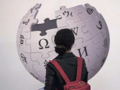 زائرة تقف أمام شعار منصة الموسوعة الإلكترونية "ويكيبيديا" في فرانكفورت  - AFP