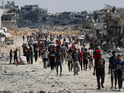فلسطينيون يسيرون بين الأنقاض بعد انسحاب القوات الإسرائيلية من خان يونس جنوبي قطاع غزة. 10 أكتوبر 2025 - REUTERS