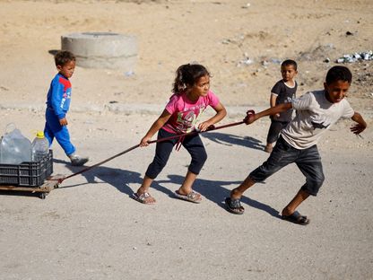 أطفال فلسطينيون يجرون عبوات مياه في مدينة رفح جنوب قطاع غزة. 9 مايو 2024 - REUTERS