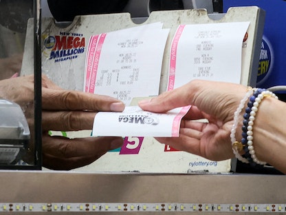 امرأة تشتري تذكرة يانصيب "Mega Millions" في كشك لبيع الصحف في مدينة نيويورك الأميركية - 26 يوليو 2022 - REUTERS