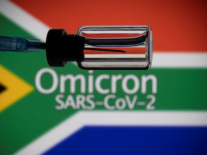 قارورة ومحقنة أمام علم جنوب إفريقيا مع كلمات تشير إلى اسم المتحور الجديد لفيروس كورونا "أوميكرون" - 27 نوفمبر 2021 - REUTERS
