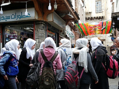 طالبات مدرسة يقفن أمام أحد المحال التجارية في دمشق القديمة - REUTERS