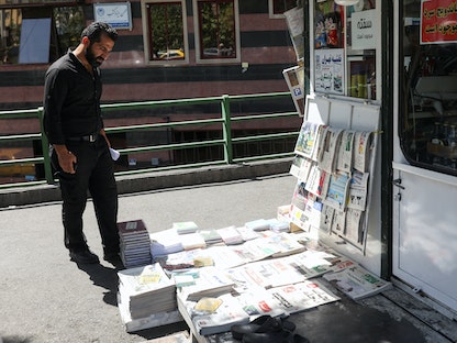رجل يشاهد الصحف في العاصمة الإيرانية طهران - 16 أغسطس 2022 - via REUTERS