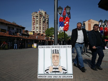 أشخاص يمشون أمام لافتة تصور رجل الدين التركي المقيم في الولايات المتحدة فتح الله غولن، قبل زيارة الرئيس التركي رجب طيب أردوغان إلى صربيا. 11 أكتوبر 2017 - REUTERS