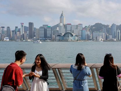 سائحون من البر الرئيسي الصيني يلتقطون صورة للمباني في تسيم شا تسوي في هونج كونج، الصين. 2 مايو، 2023 - Reuters