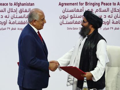 القيادي في "طالبان" الملا عبد الغني برادار والمندوب الأميركي زلماي خليل زاد يتصافحان بعد إبرام اتفاق الدوحة في 29 فبراير 2020 - AFP