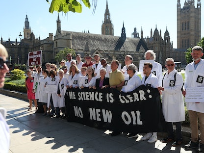علماء يحملون لافتات تطالب بإنهاء منح الحكومة تراخيص جديدة لإنتاج النفط والغاز في المملكة المتحدة بالقرب من مجلسي البرلمان في لندن. 4 سبتمبر 2023 - AFP