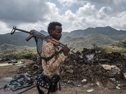 أحد أفراد القوات الإريترية يقف أمام حطام منزل في ضواحي قرية بيسوبر بإقليم تيغراي، إثيوبيا  - AFP