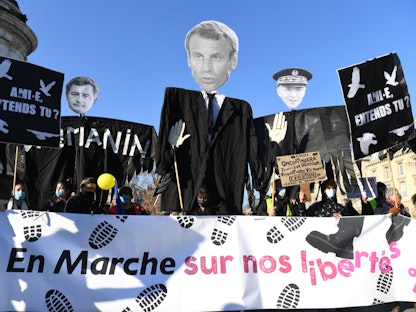 متظاهرون يحملون لافتات وصور للرئيس الفرنسي ووزير الداخلية احتجاجًا على عنف الشرطة - AFP
