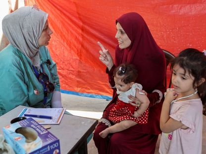 طبيبة فلسطينية تستعد لفحص أطفال نازحين في خيمة بالقرب من دير البلح وسط قطاع غزة. 12 أغسطس 2024 - REUTERS