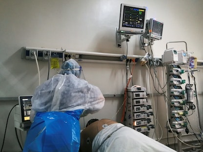 أحد أعضاء الطاقم الطبي يساعد مريضاً مصاباً بكورونا في قسم العناية المركزة بأحد مستشفيات أريانة. تونس 26 أبريل 2021  - REUTERS