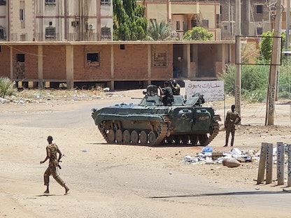 جنود من الجيش السوداني يسيرون قرب مركبة مدرعة في أحد شوارع جنوبي الخرطوم- 6 مايو 2023 - AFP