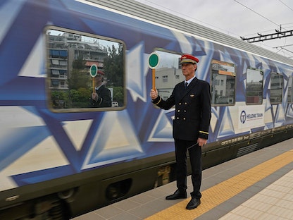 رئيس المحطة يحمل لوحة مرور أمام أول قطار مغادر من محطة أثينا الرئيسية إلى ثيسالونيكي- 3 أبريل 2023. - AFP