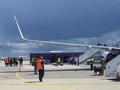 موظفون ورجال أمن على مدرج مطار مينسك أمام طائرة "راين إير" التي أُرغمت على الهبوط في بيلاروسيا، 23 مايو 2021 - REUTERS