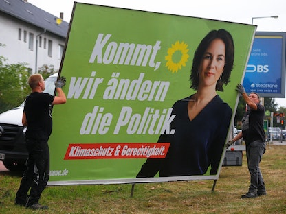 عمال يزيلون لافتة دعائية لزعيمة حزب الخضر أنالينا بيربوك بعد انتهاء الانتخابات الألمانية - 27 سبتمبر 2021 - REUTERS