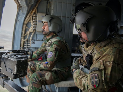 مقاتلان في سلاح الطيران الأفغاني يستقلان مروحية من طراز (Mi 17) خلال مهمة تدريبية في قندهار- 3 مارس 2016 - REUTERS
