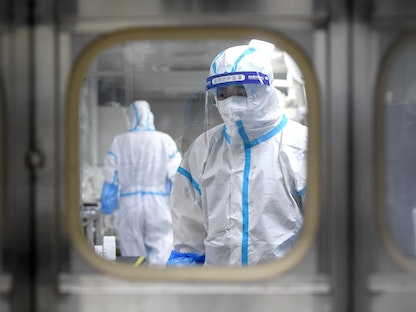 علماء يتعاملون مع عينات الحمض النووي داخل مختبر بمدينة ووهان الصينية - VIA REUTERS