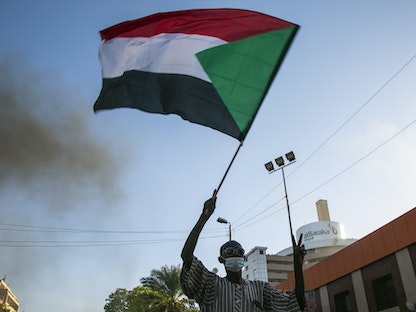 متظاهر يحمل علم السودان في ذكرى الاحتجاجات التي أطاحت بالرئيس السابق عمر البشير في العاصمة الخرطوم - 19 ديسمبر 2020 - Getty Images