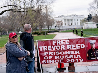 عائلة الجندي الأميركي المسجون في روسيا تقف أمام لافتة تطالب بالإفراج عنه. 30 مارس 2020. - AFP